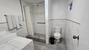a white bathroom with a shower and a toilet at Motel Olvera in Tijuana +2 photos