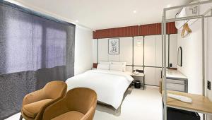 a bedroom with a white bed and two chairs at 그루브 호텔 Groove Hotel in Jeonju
