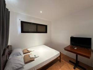 a small bedroom with a bed and a television at Balay Inato Pension in Puerto Princesa City