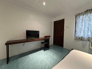 a room with a desk with a television and a door at Balay Inato Pension in Puerto Princesa City +9 photos