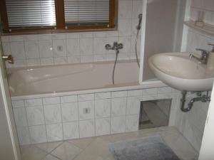 a bathroom with a sink and a bath tub next to a sink at Ferienwohnung Huber in Opfenbach +18 photos