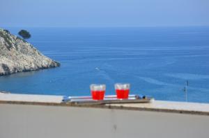 - deux verres de boissons rouges assis sur une table donnant sur l'océan dans l'établissement Casa Bellavista, à Castro di Lecce