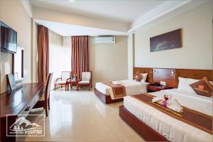a hotel room with two beds and a desk at Duy Tân Quảng Bình Hotel & Resort in Dong Hoi