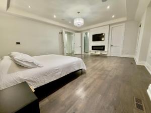 a white bedroom with a large bed and a television at Modern Luxury Living in Toronto