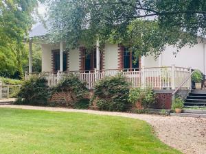 a white house with a porch and a yard at The Secret Garden Burradoo in Burradoo
