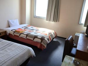 a hotel room with two beds and a window at Asahikan in Kofu