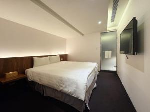 a hotel room with a bed and a flat screen tv at Goodmore Hotel in Taipei