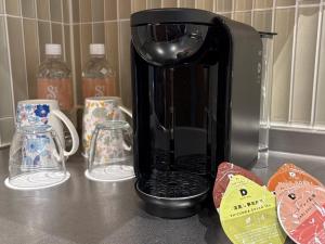 a coffee maker sitting on a counter next to cups at The Moana in Chatan