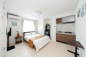 a bedroom with a white bed and a kitchen at SAIEI Hotel 东京小岩 JR京成双站直达成田羽田迪士尼适合家庭团队整栋多房型 in Tokyo