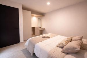 a bedroom with a large white bed with pillows at Luke Stay in El Pueblito
