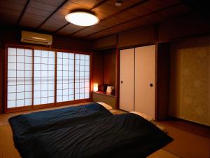 a bedroom with a bed and two windows at Villa near Kinkakuji Pets OK free Parking 金閣寺周辺 貸切町屋 ペットOK 無料駐車場 in Kinugasa