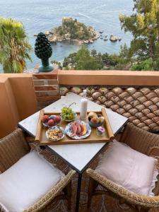 a table with a tray of food on a balcony at La Bergerie Isolabella sea view B & B in Taormina