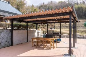 a wooden pergola with a table and chairs on a patio at 将軍の隠れ家 in Okayama