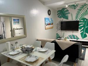 a living room with a table and chairs and a tv at Tropical Themed 2 Bedroom Condo in Mandaue City