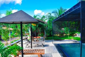a patio with benches and an umbrella next to a pool at Jungle View Inn in Trincomalee