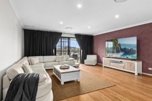 a living room with a white couch and a tv at Coastal Blue in Windang