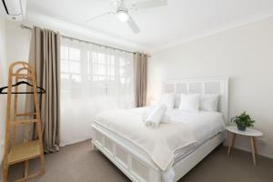 a white bedroom with a white bed and a ladder at Coastal Blue in Windang +16 photos