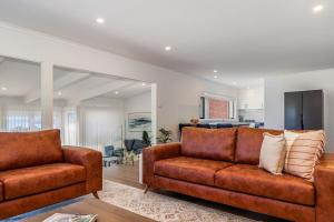 a living room with two brown couches and a kitchen at 180 Degrees - Amazing Bay Views in St Helens