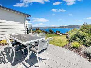 a table and chairs on a patio with a view of the water at 180 Degrees - Amazing Bay Views in St Helens