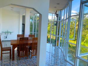a dining room with a table and chairs and windows at Haritha Villa Yala in Kirinda