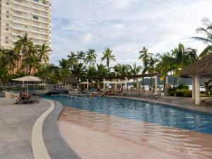 a swimming pool at a resort with palm trees at Luxe Oceanfront Condo in Golden Zone in Mazatlán