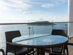 a glass table and chairs on a balcony overlooking the water at Luxe Oceanfront Condo in Golden Zone in Mazatlán