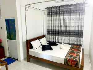 a bedroom with a bed with black and white pillows at Haritha Villa Yala in Kirinda