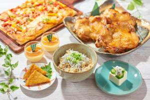 a table topped with dishes of food and a pizza at Hiroshima Tokyu REI Hotel in Hiroshima