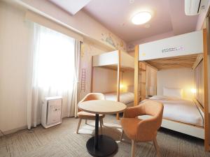 a room with a bed and a table and chairs at Hiyori Hotel Maihama in Urayasu