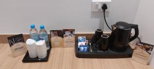 a counter with a coffee pot and bottles of water at Hotel Grand Avenue in Pāmbādi +3 photos