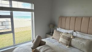 a bedroom with a large bed and a large window at Blue-breaker view in Struisbaai