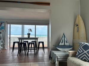 a living room with a table and chairs and a surfboard at Blue-breaker view in Struisbaai