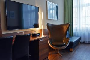 a room with a desk with a chair and a television at Arthotel Munich in Munich