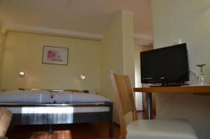 Schlafzimmer mit einem Bett und einem Flachbild-TV in der Unterkunft Pension Konditorei Cafe Dora in Münchberg