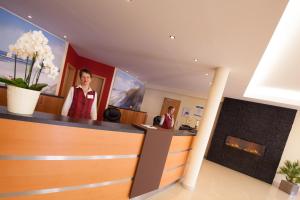 two women in a salon with a fireplace at Moin Hotel Cuxhaven in Cuxhaven