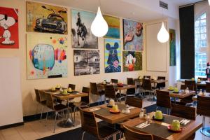 a restaurant with wooden tables and chairs and pictures on the walls at Arthotel Munich in Munich