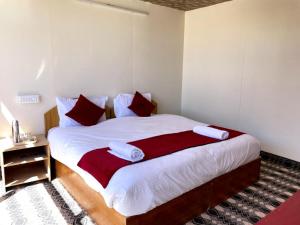 a bedroom with a large bed with red and white pillows at zoz camp pangong lake in Lukung +1 photo