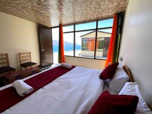a bedroom with a large bed with a large window at zoz camp pangong lake in Lukung