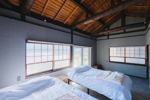 two beds in a room with two windows at oribe guesthouse in Tajimi
