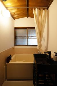 a bathroom with a tub and a sink and a window at oribe guesthouse in Tajimi +81 photos