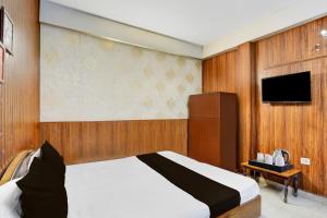a bedroom with a bed and a flat screen tv at Super Hotel O Dehradun City Centre Formerly Downtown in Dehradun