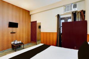 a hotel room with a bed and a tv at Super Hotel O Dehradun City Centre Formerly Downtown in Dehradun