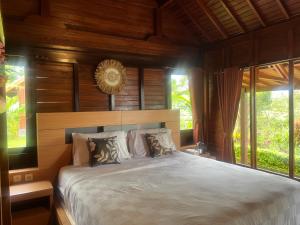 a bedroom with a large bed with wooden walls and windows at Pondok Kayu Pathavi in Baturiti
