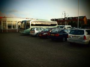 a group of cars parked in a parking lot with a bus at Hotel Zwanenburg Amsterdam Airport in Zwanenburg