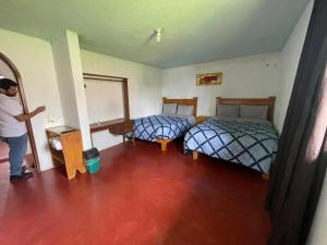 a man is standing in a room with two beds at Casa de campo en Zacatlán in Zacatlán