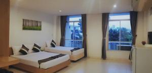 a hotel room with two beds and a large window at Sena House in Bangkok