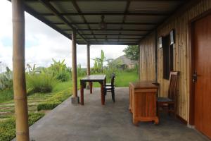 a porch with a table and chairs and a desk at Pondok Kayu Pathavi in Baturiti