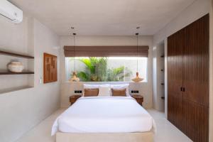 a bedroom with a large white bed and a window at Heritage Villas in Uluwatu