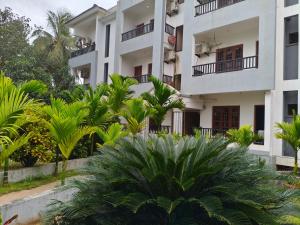 an apartment building with palm trees in front of it at Jackfruit in Arambol