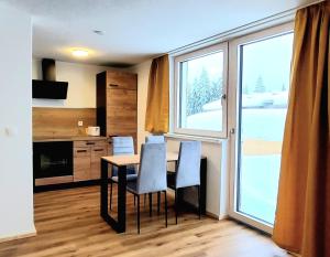 a kitchen with a table and chairs and a large window at Alpenrose Ferienwohnung in Balderschwang